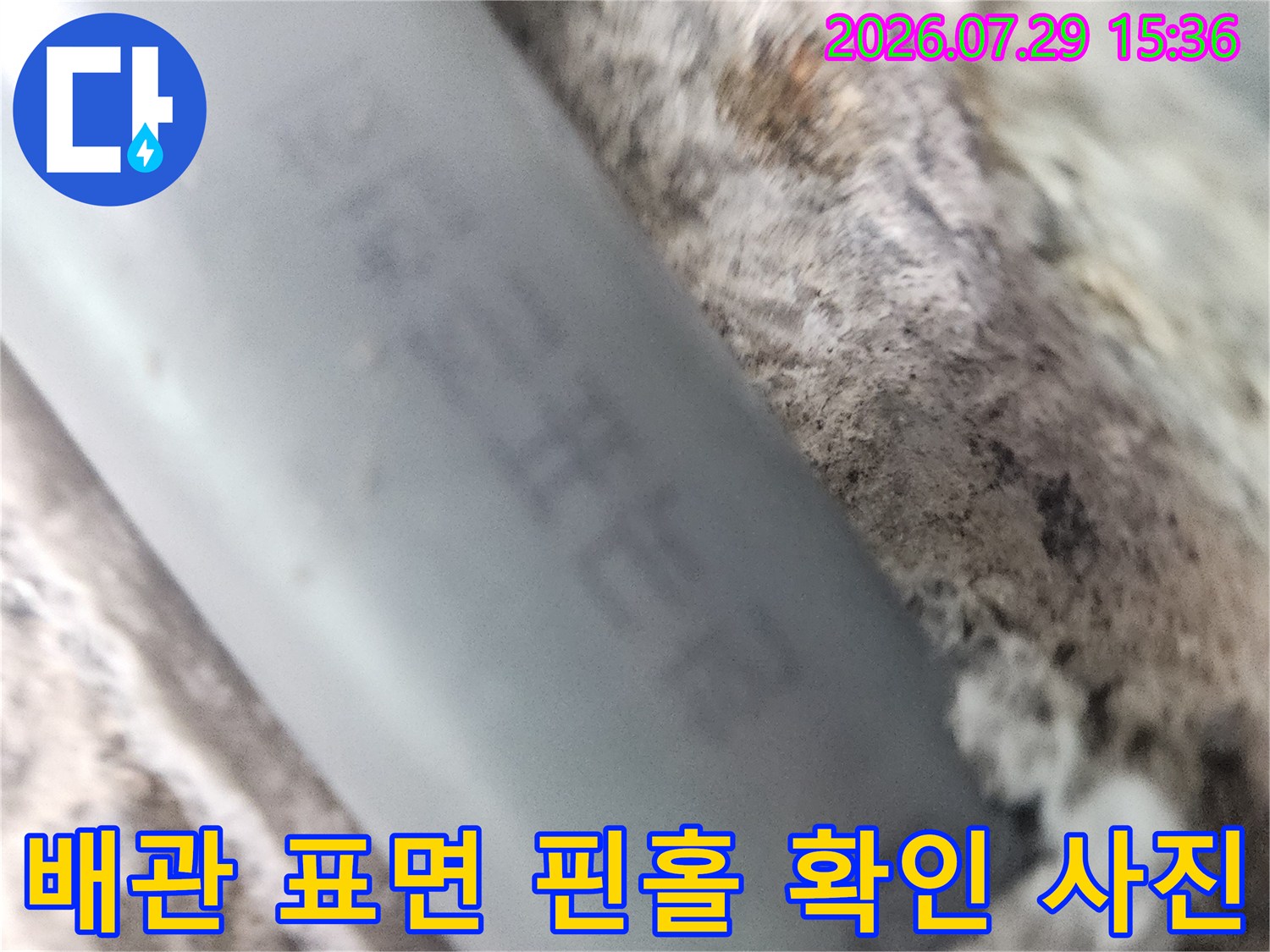 회색 배관의 손상된 부위를 가까이서 촬영하여 누수 지점을 명시함