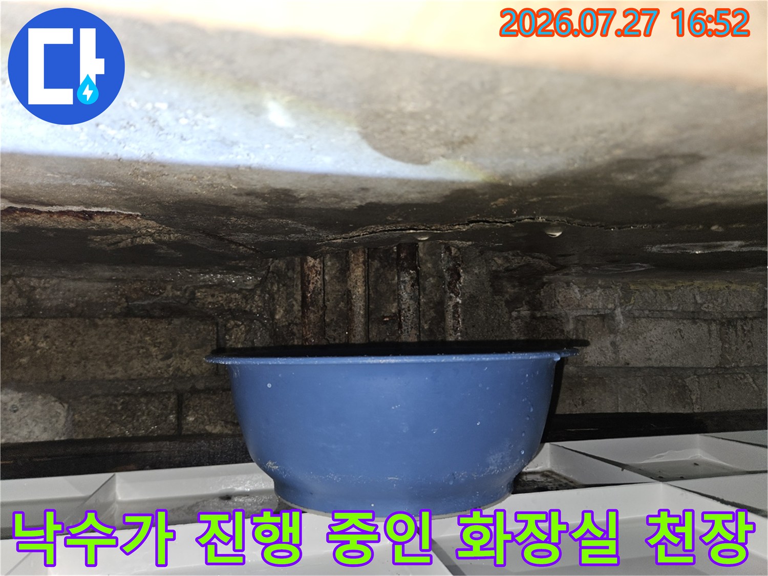 콘크리트 천장에서 물이 새어 나와 파란색 대야에 물이 고여 있는 누수 현장 사진