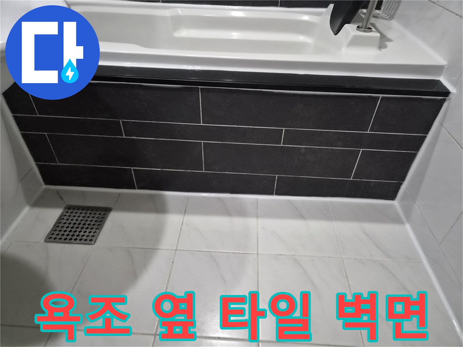 어두운색 타일로 마감된 욕조 옆면 벽체