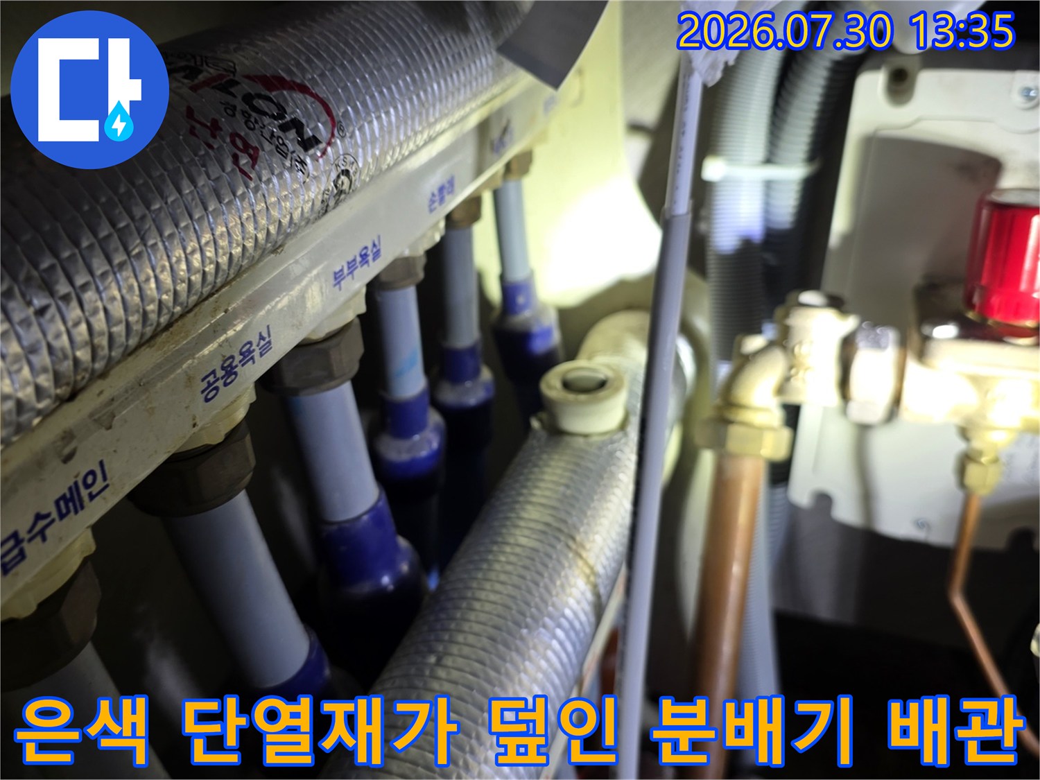 단열재로 감싸진 은색 온수 배관과 분배기 구성품들