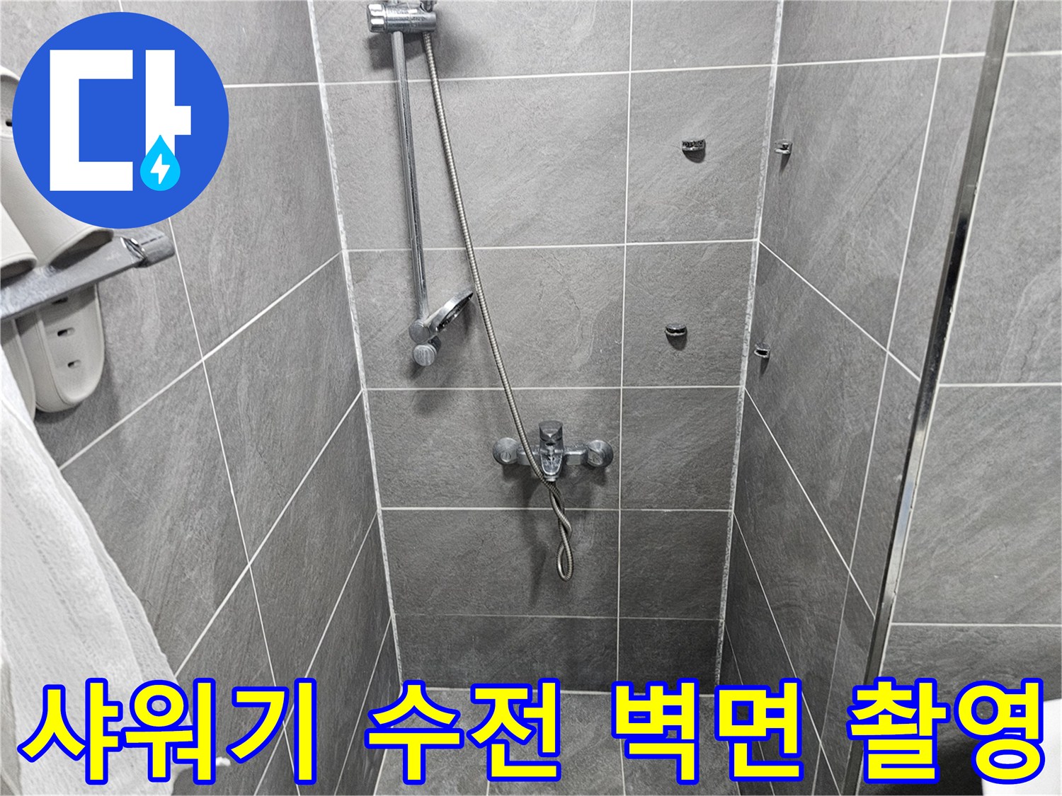 샤워기 호스와 수전이 설치된 회색 타일 벽면