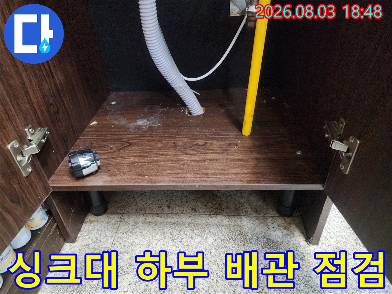 싱크대 하단부 노란색 배관과 유연한 호스 연결 부위 점검 장면