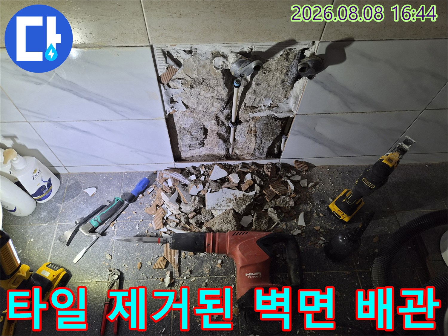 화장실 타일을 파쇄하여 드러난 샤워기 수전 연결 배관과 작업 도구들
