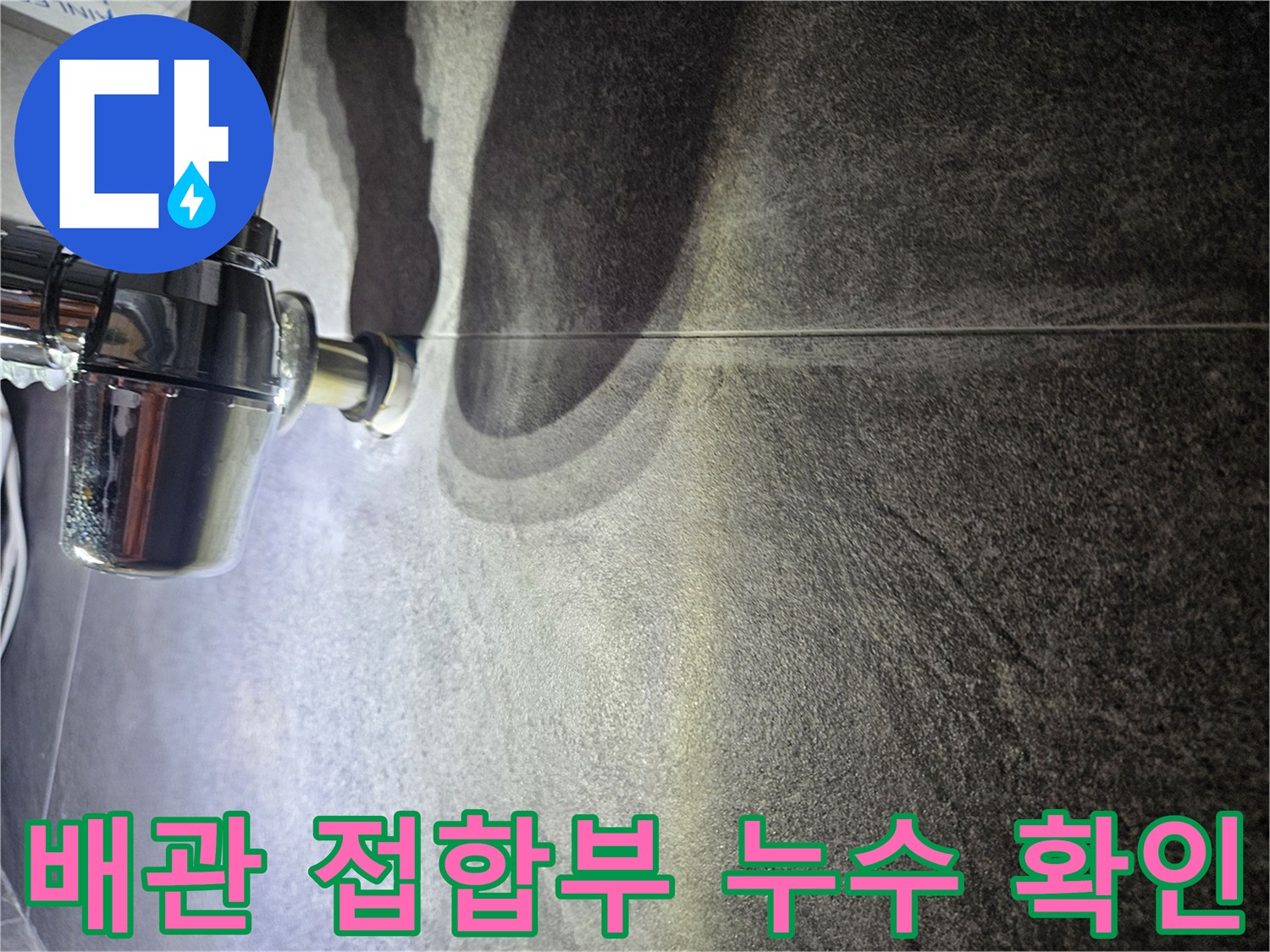 어두운 색 타일 벽과 크롬 도금 배관의 연결 부위
