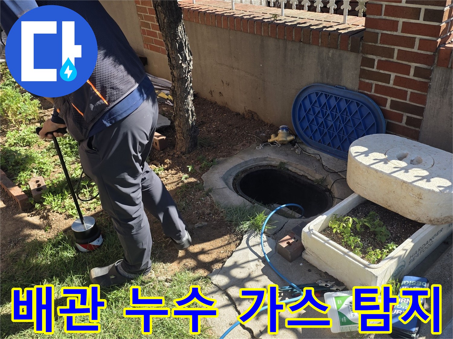 파란색 호스가 연결된-가스 탐지기로 지면 아래 배관을 조사합니다.