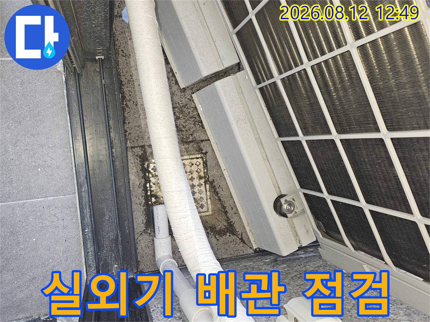 에어컨 실외기 본체와 연결된 흰색 보온재 배관의 모습입니다.