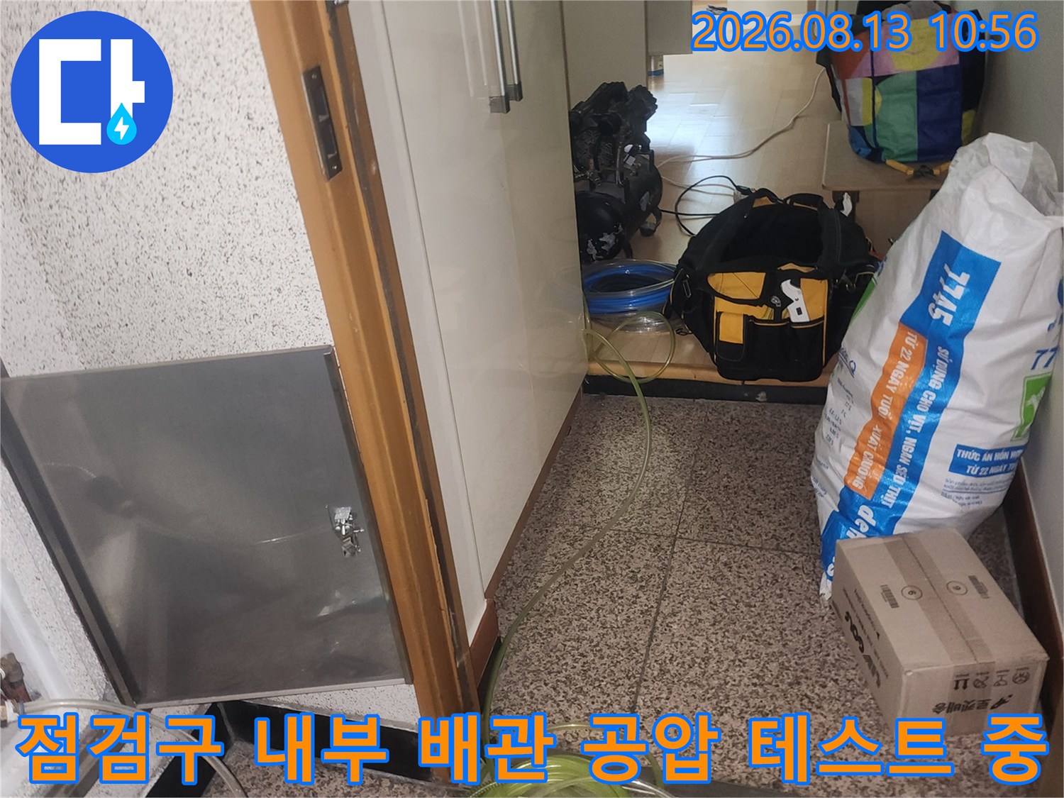 바닥의 금속 점검구 틈새로 연결된 누수 탐지용 노란색 호스와 측정 장치들