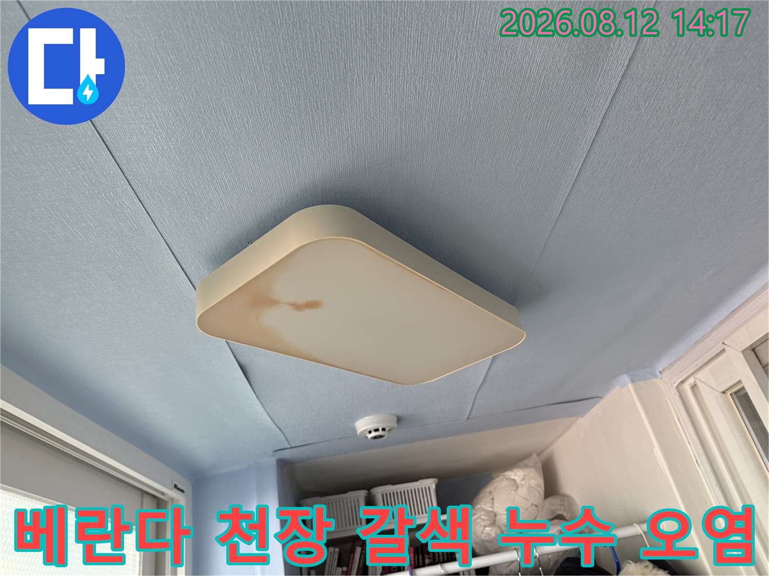 하늘색 베란다 천장의 조명 덮개 좌측면에 발생한 누수 얼룩 사진