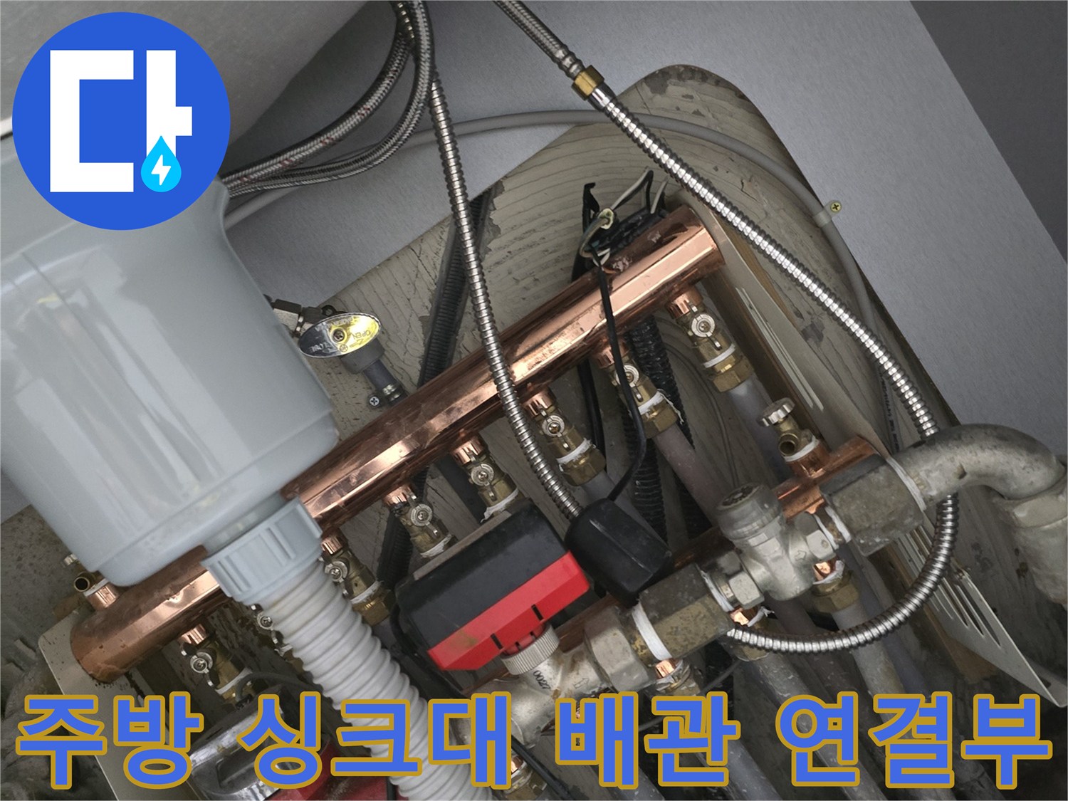 싱크대 하부장의 낡은 수전 호스와 금속 배관 부품들