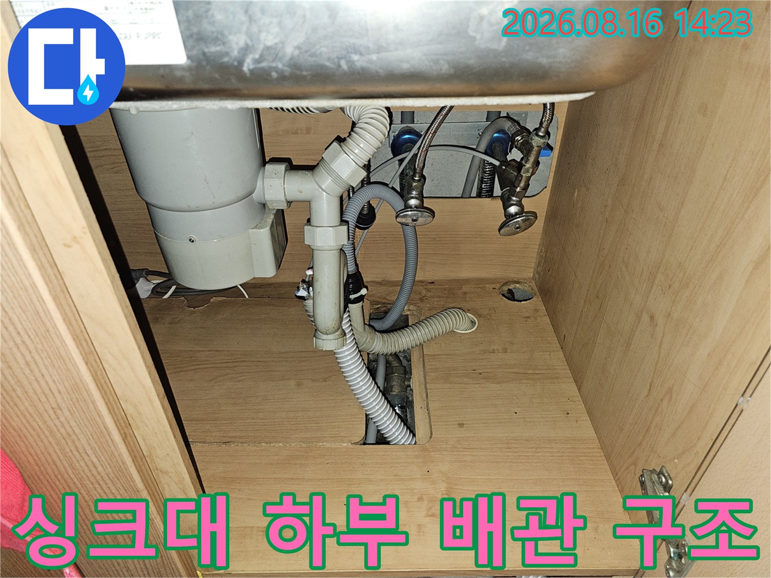 싱크대 아래쪽의 복잡한 배관 연결 부위와 하수관 모습