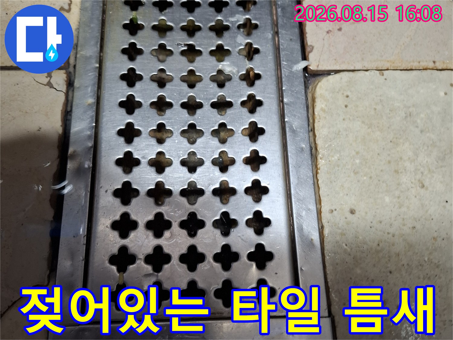 물기가 스며든 트렌치 주변의 타일과 스테인리스 마감재 상세 사진