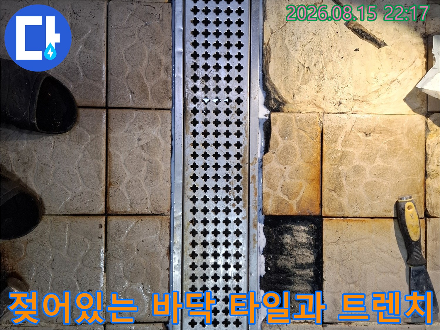 스테인리스 배수구 주변의 젖은 타일과 물기가 스며든 모습