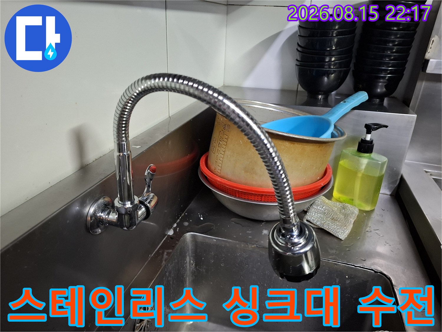 식당 주방의 스테인리스 싱크대와 구부러진 형태의 수전입니다.