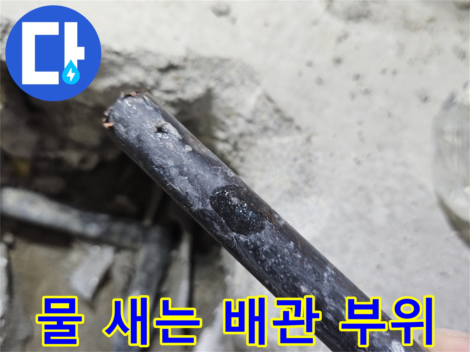 콘크리트 아래 노출된-습기가 묻어 있는 검은색 수도 배관