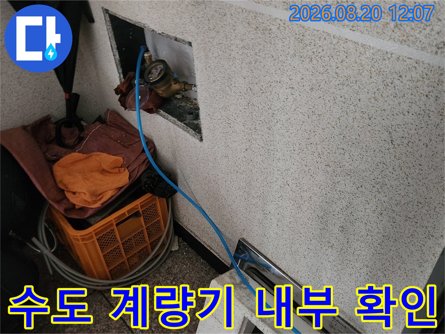벽면 매립된 수도 계량기와 파란색 점검 호스