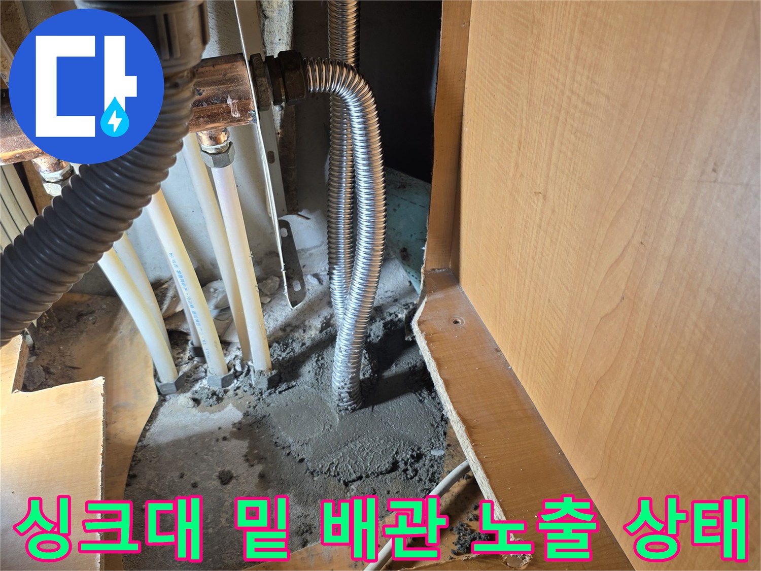싱크대 아래 젖은 바닥과 연결된 금속 배관의 모습