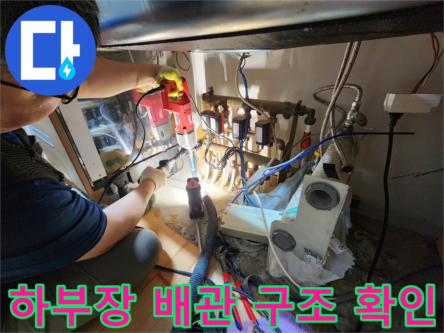 싱크대 하단부의 복잡한 급수 및 배수 배관 연결 상태 사진
