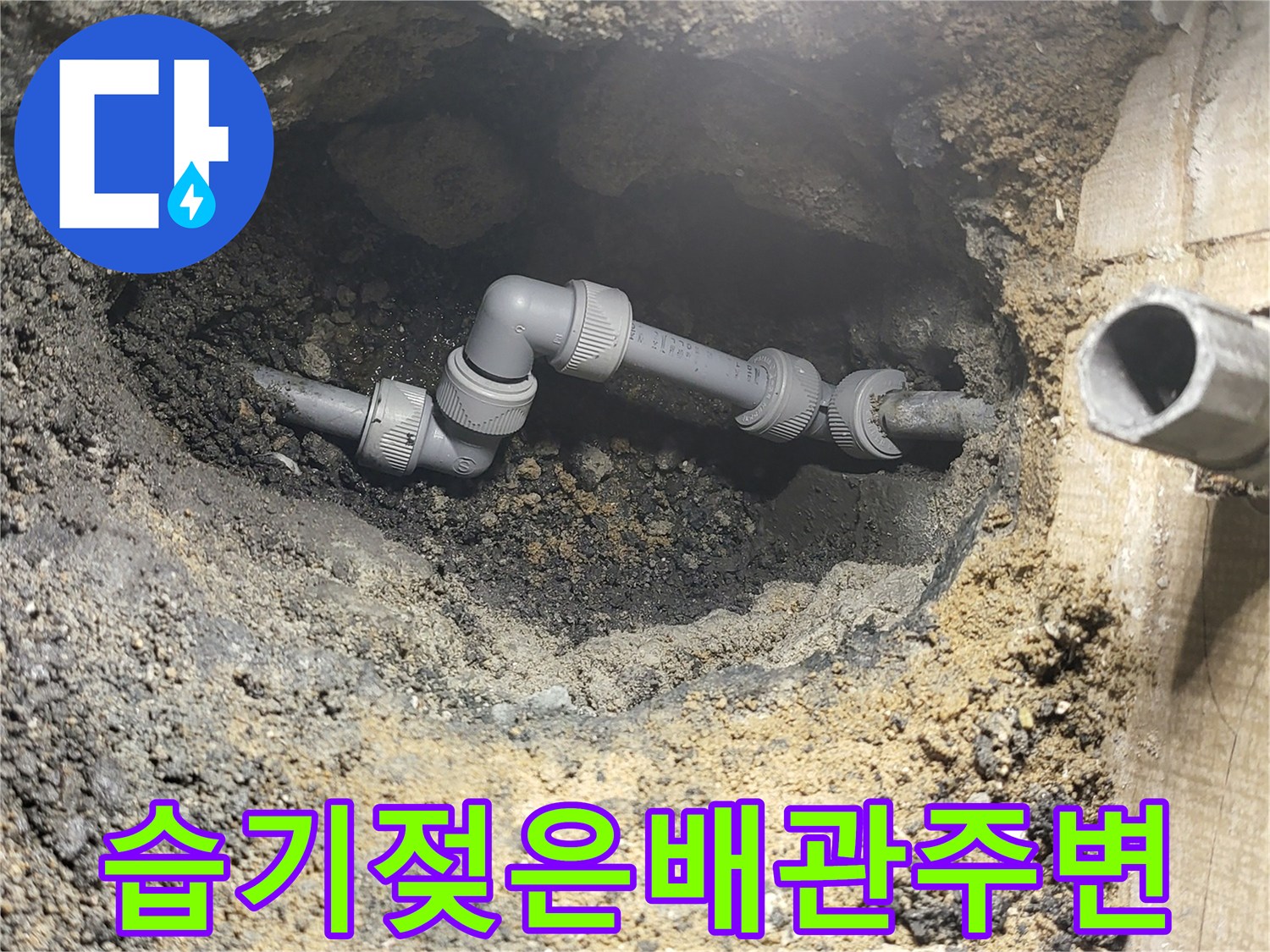 물에 젖어 검게 변한 흙과 노출된 배관 부속