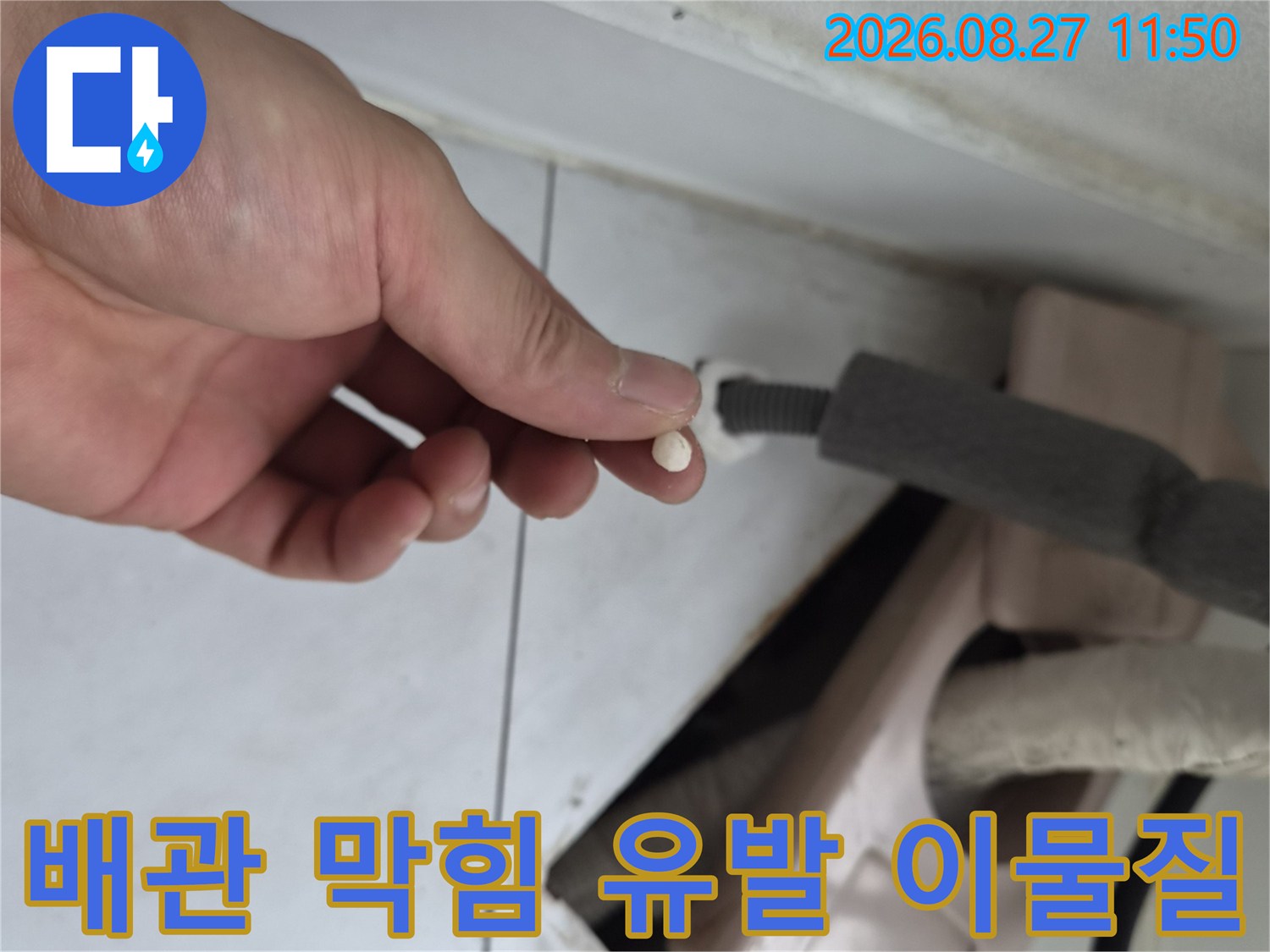 손가락으로 집어 올린 배관 내부의 작은 오물 덩어리