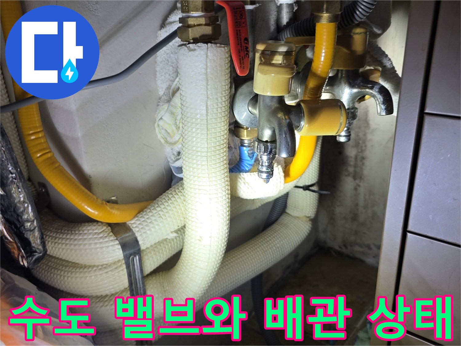 노란색 보온재가 적용된 싱크대 하단 배관 및 금색 수도 부속