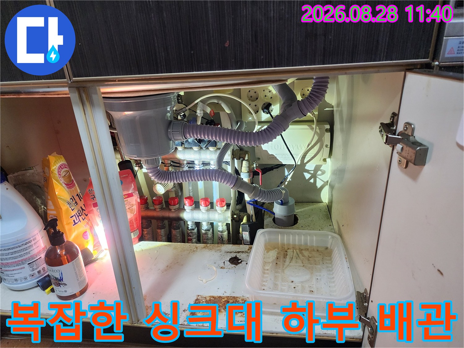 싱크대 아래쪽 정수기 필터와 에어컨 드레인 호스가 얽힌 배관 상태