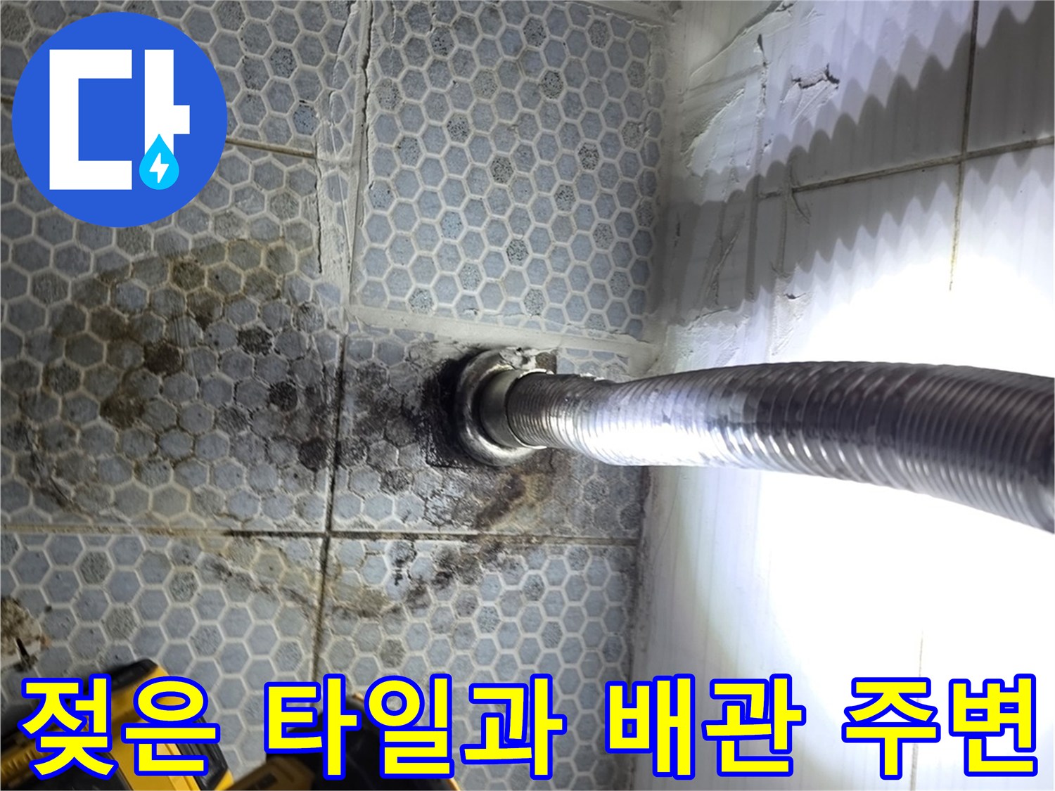 바닥 배관 연결 부위의 젖은 타일과 얼룩진 모습