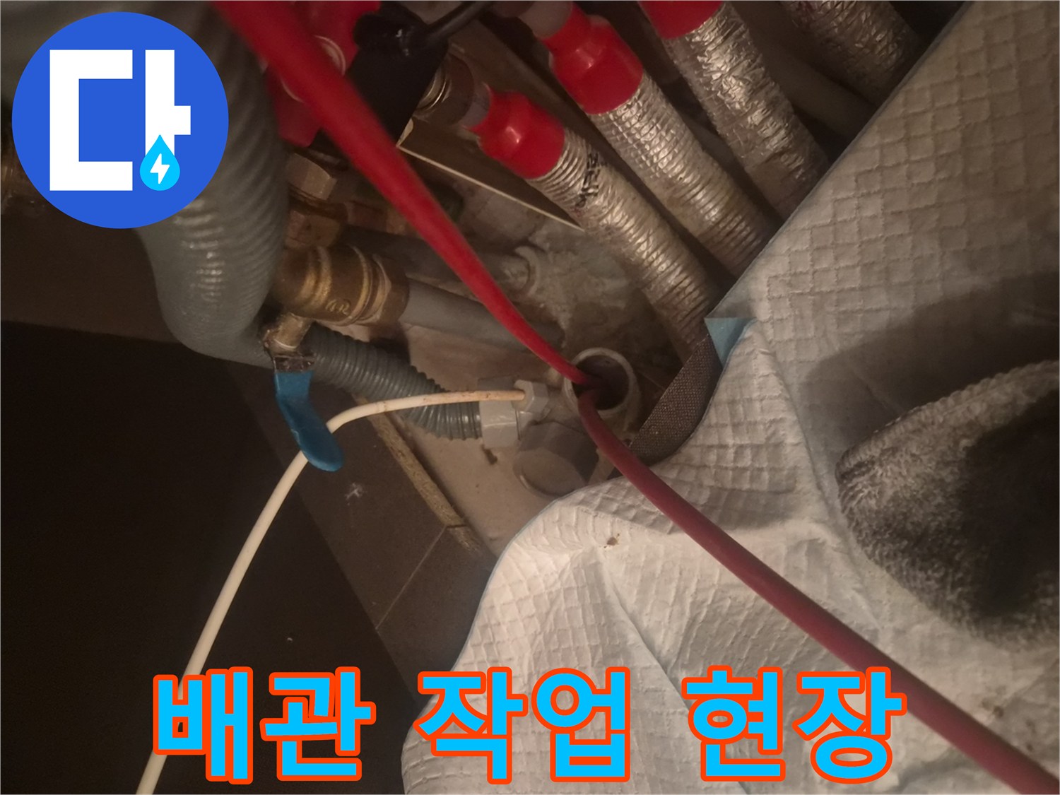 싱크대 아래 복잡하게 얽힌 보온재 배관과 호스 연결부