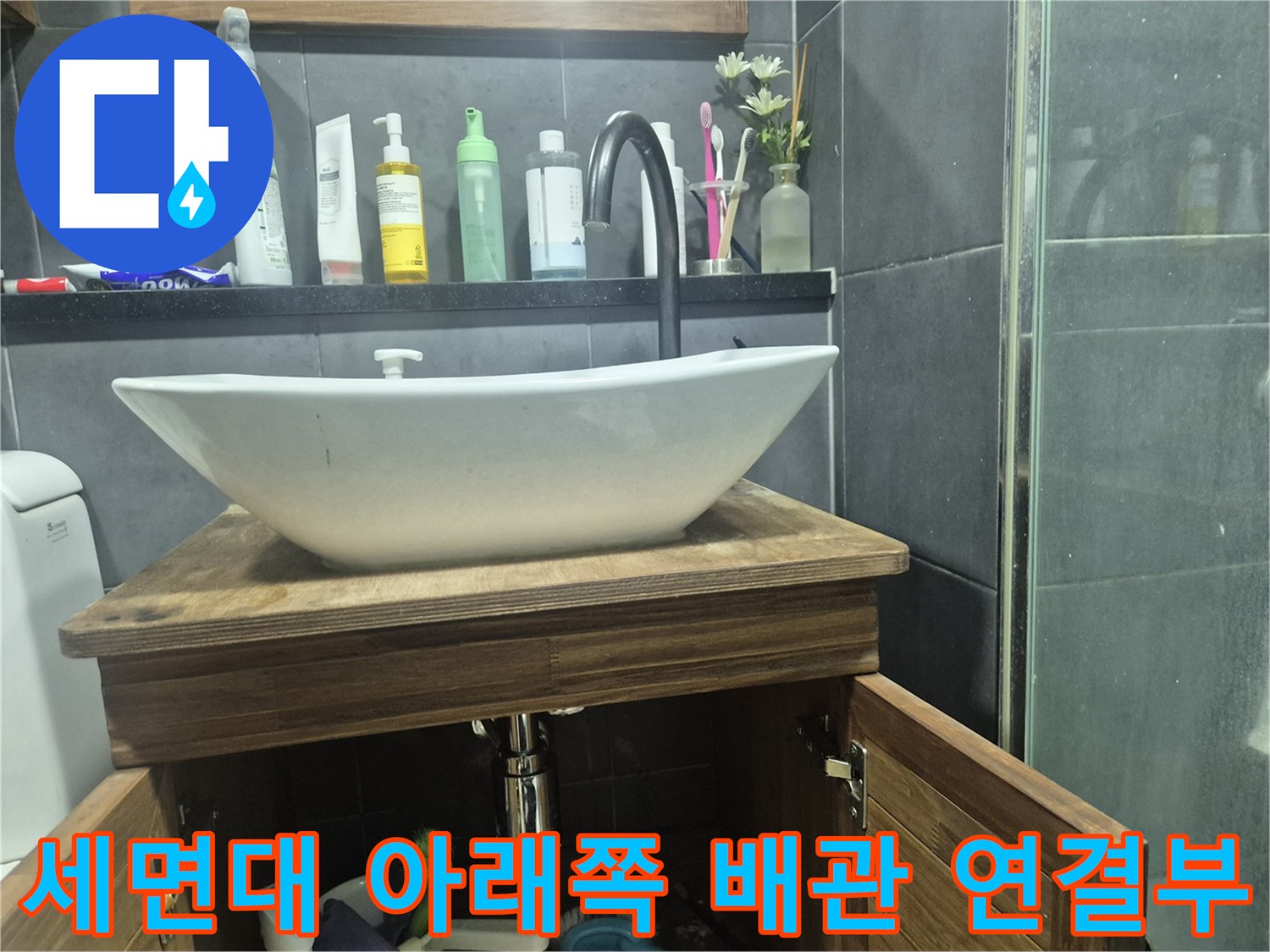 하얀 세면대와 연결된 은색 금속 배관 부위