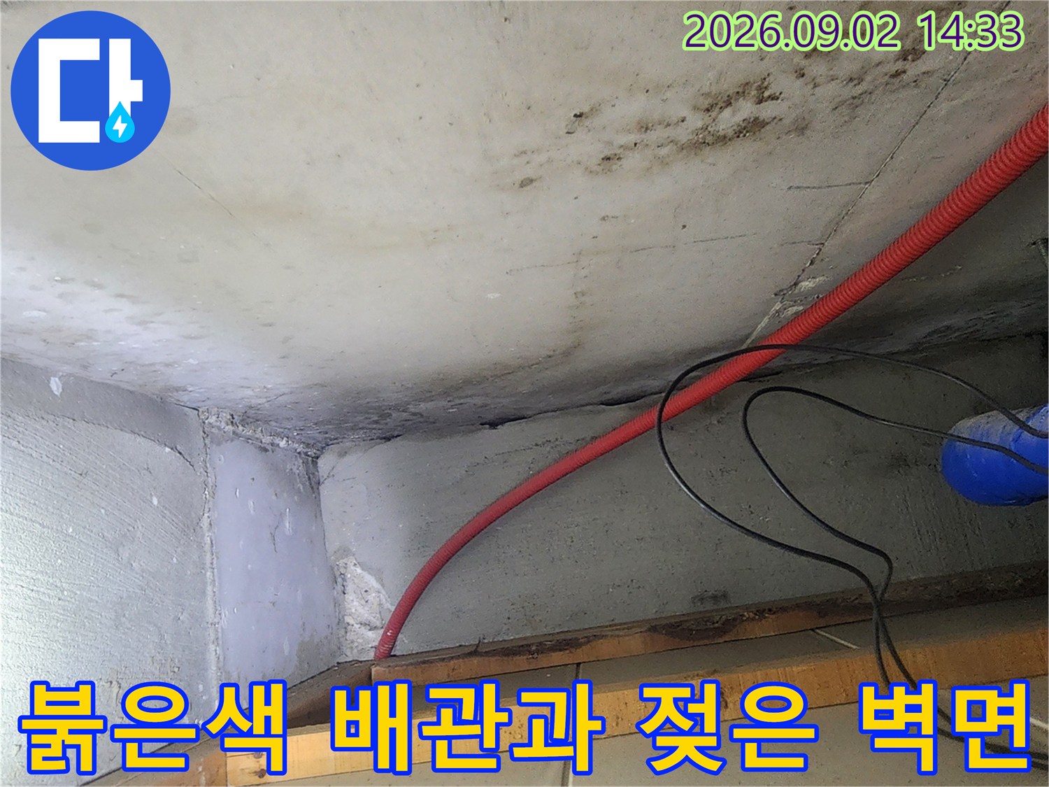 천장을 지나가는-붉은색 배관 주변의 습기 찬 벽면입니다.