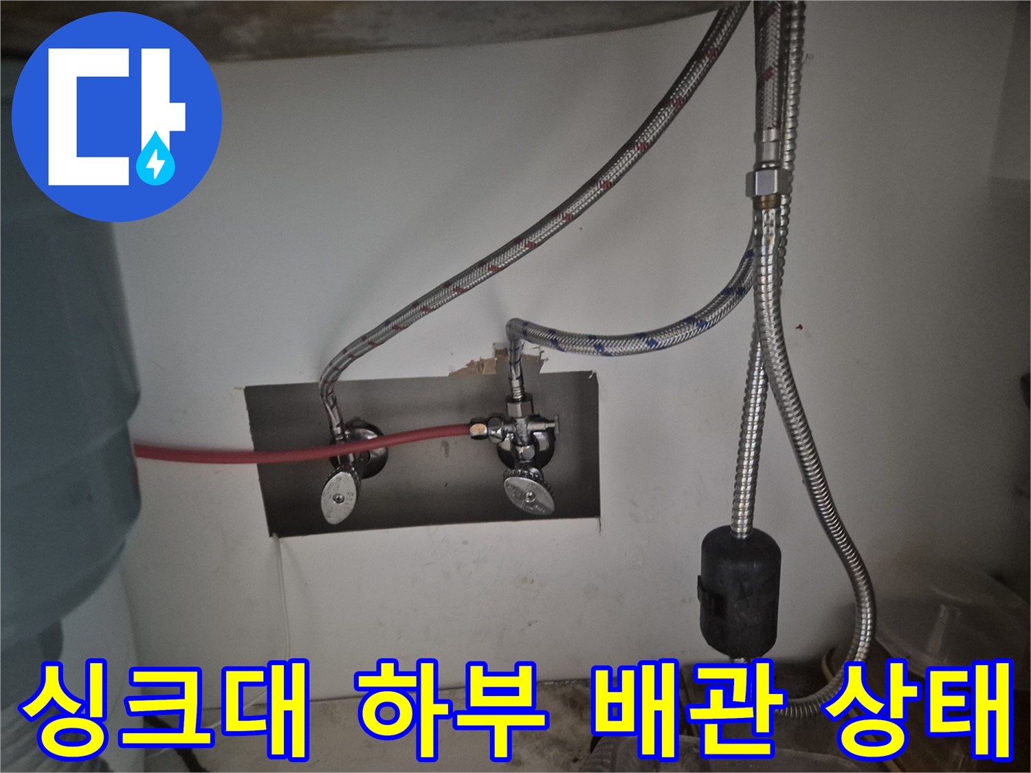 싱크대 하부장 내부에 설치된 새 수전과 고압 호스 연결 모습