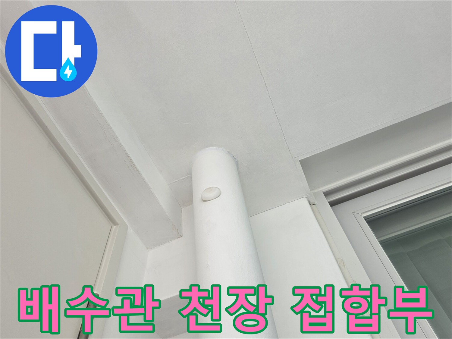 천장에 설치된 흰색 우수관의 연결 부위입니다.