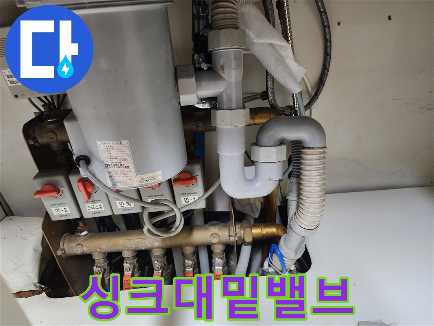 싱크대 아래 설치된 다수의 수도 밸브와 배수관