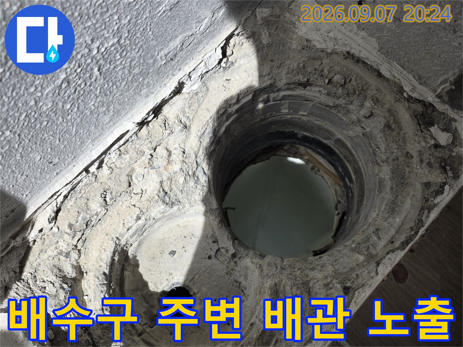 배수구 주변의 낡은 마감재와 드러난 배관 연결 부위