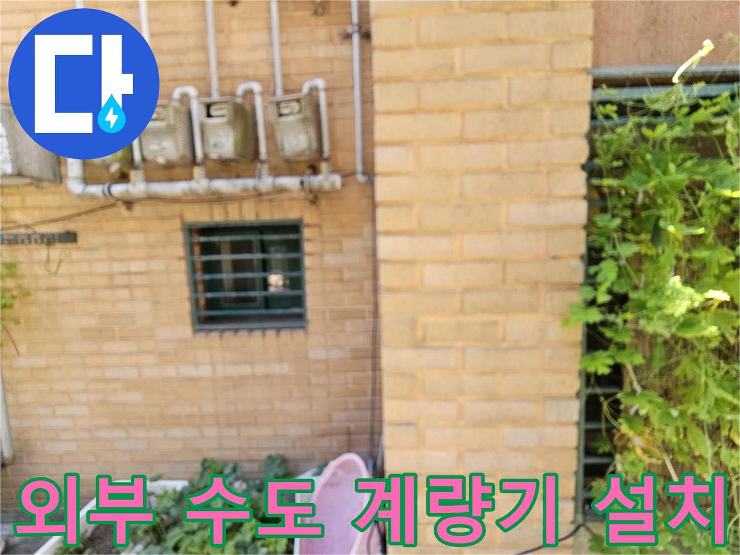 벽돌 벽면에 나열된 수도 계량기와 연결 배관의 모습입니다.