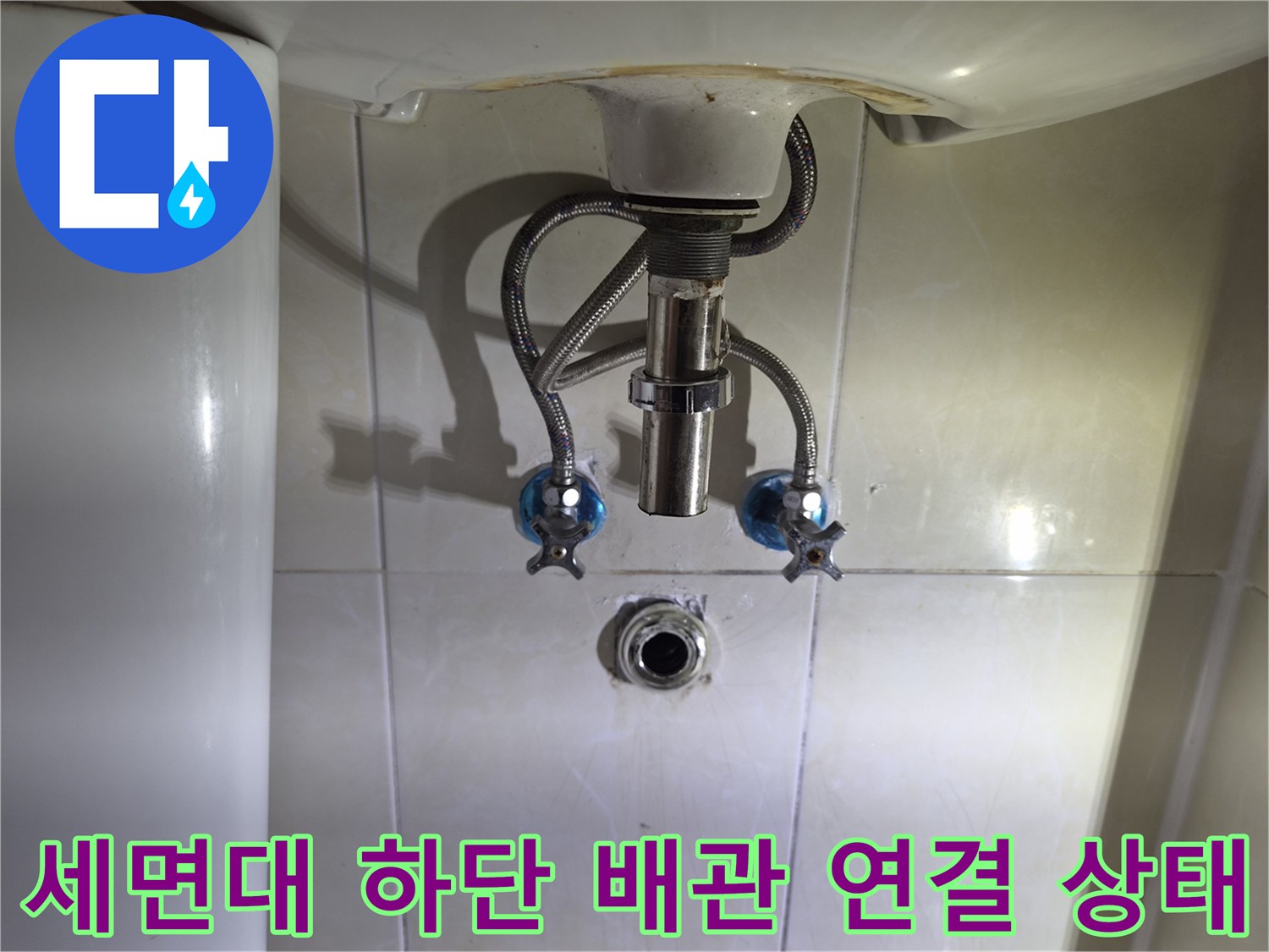 세면대 아래 벽체에 설치된 급수 밸브와 호스 부위