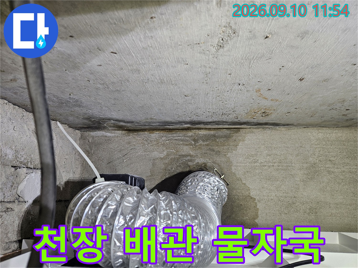 습기가 번진-콘크리트 벽면과 은색 호스 연결 지점