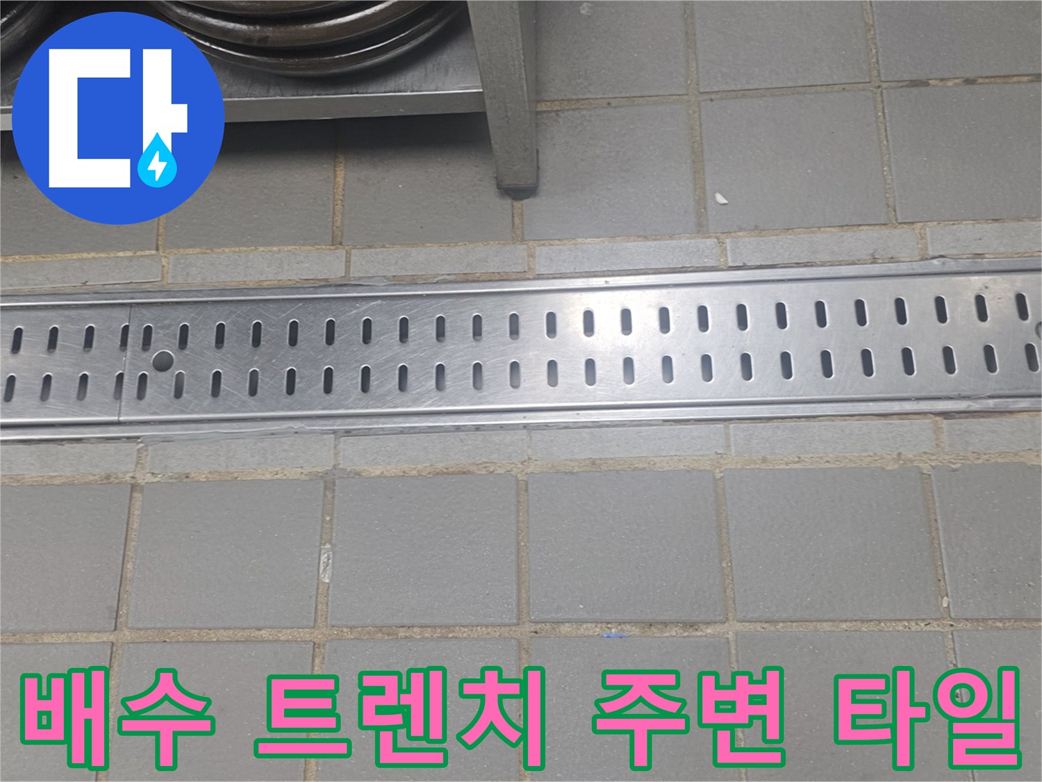 스테인리스 배수구와 회색 타일 바닥의 접합부 상세 사진