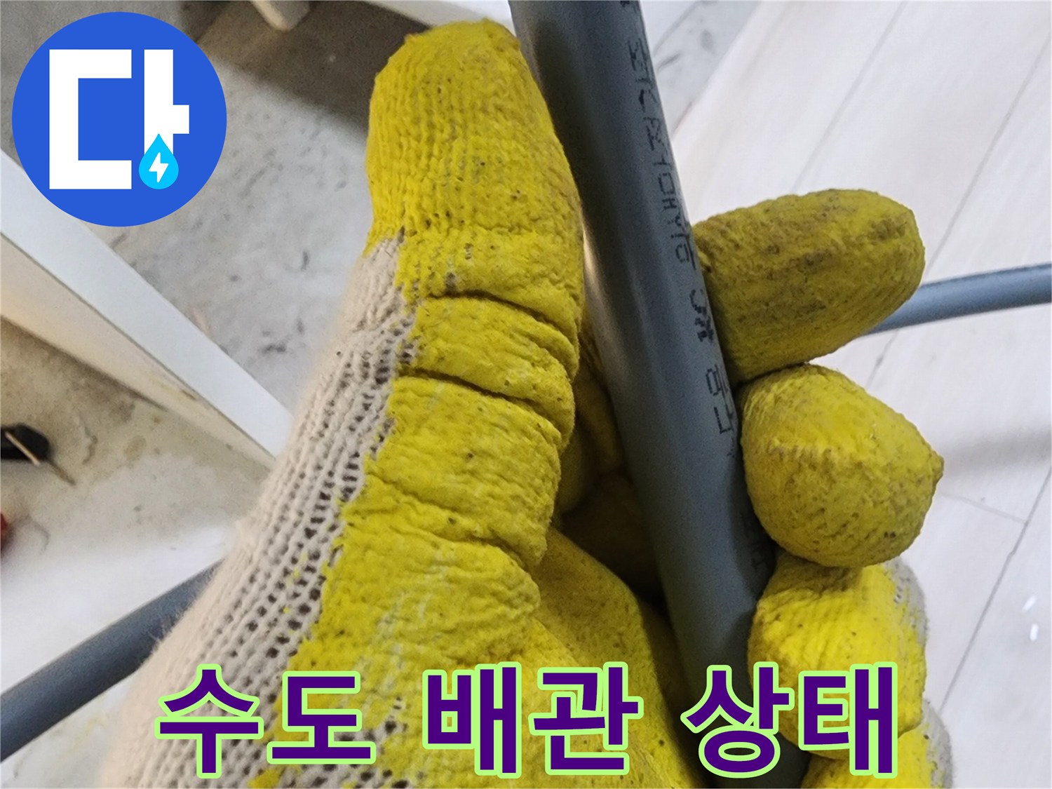 회색 배관을 쥔 작업자의 손과 주변 환경