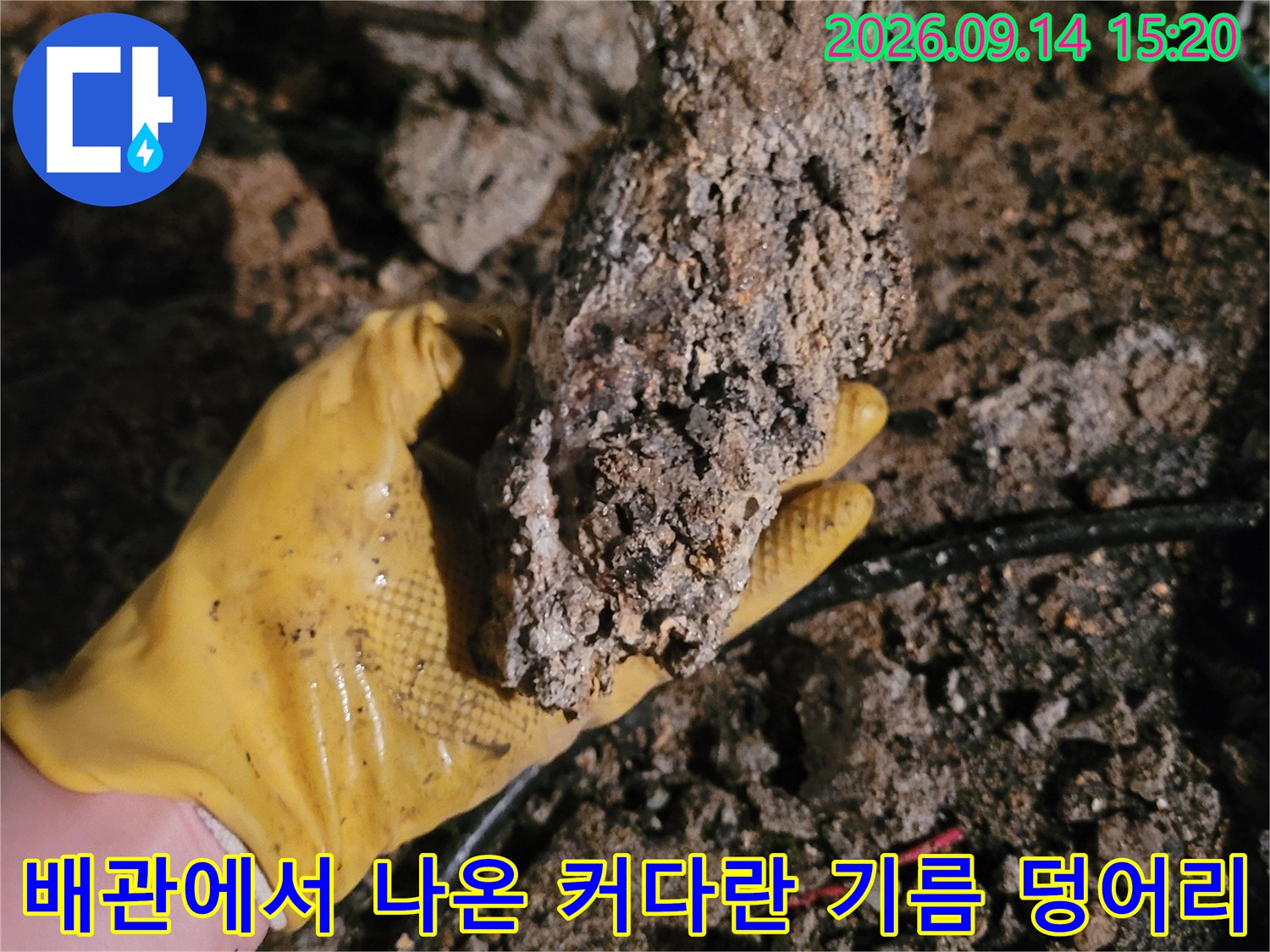 장갑을 낀 작업자가 들고 있는 배관 슬러지 뭉치