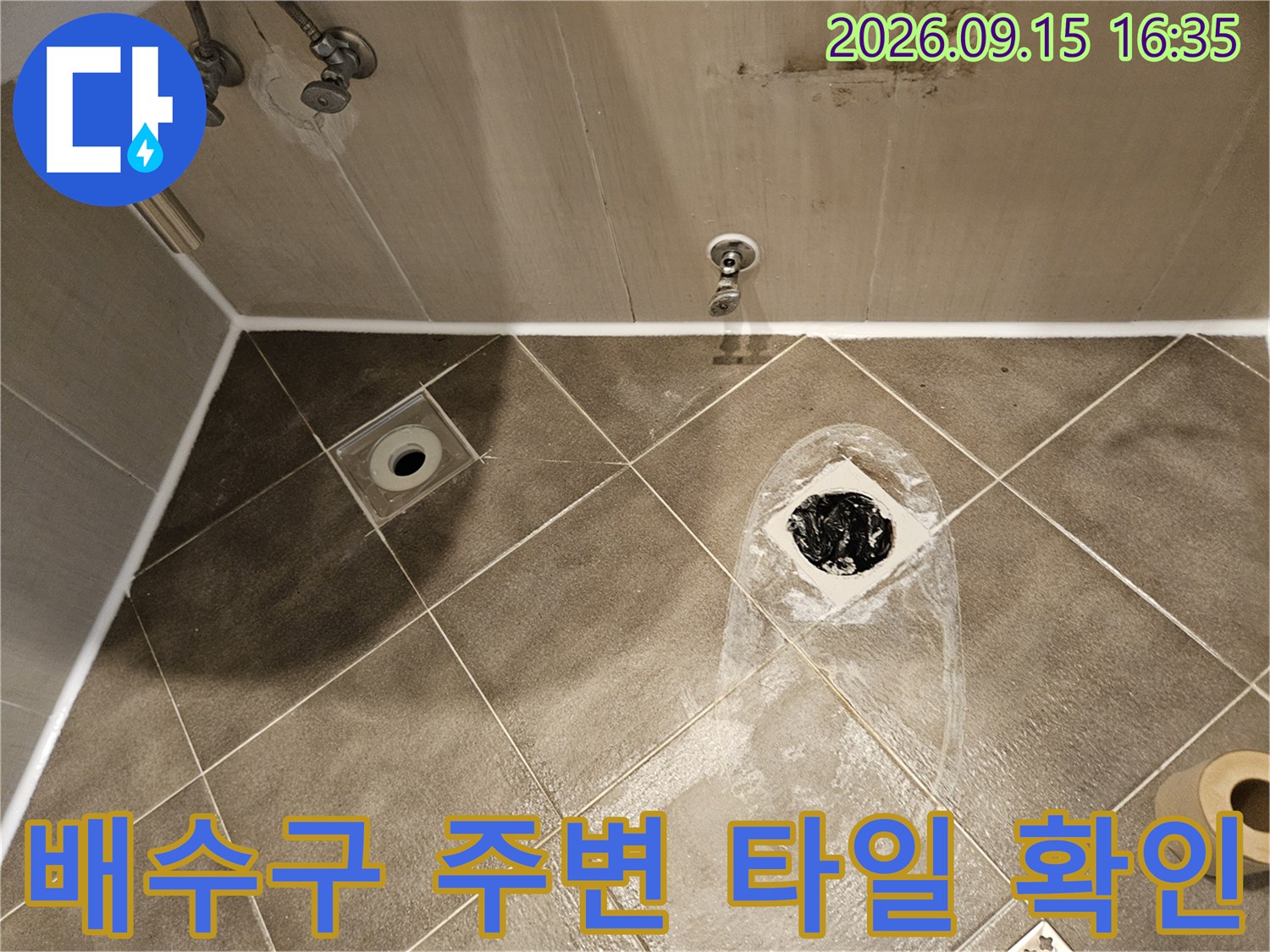 고양 일산동구 화장실 배수구 주변의 파손된 타일과 노출된 배관 상태를 점검하는 모습입니다.