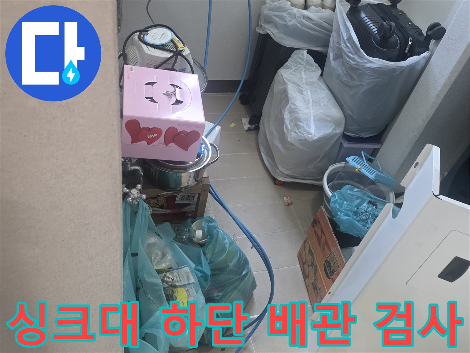 싱크대 밑 공간에 배치된 파란색 호스와 압력 측정 장비의 모습입니다.