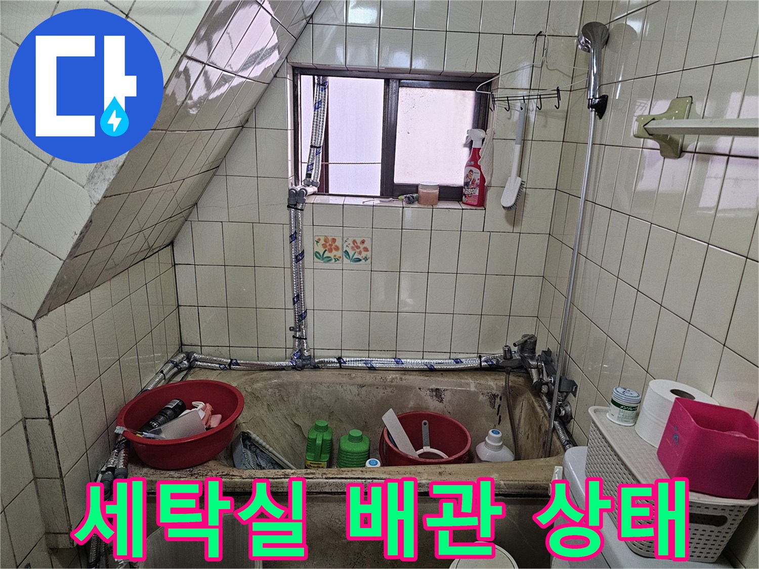 타일 벽면에 노출된 수도 배관과 호스 연결 부위